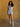 Shannon Denim Romper, collared cap-sleeve romper with zip-up front, waist belt, front and back pockets, lightweight denim, and stretch fabric.